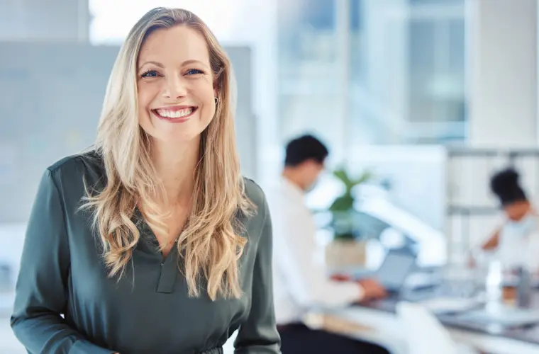 A smiling blonde woman in an office.